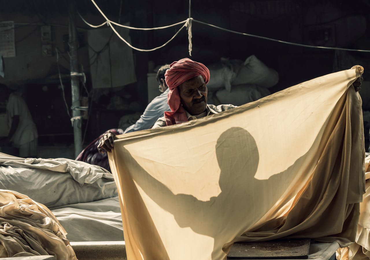 An Indian washerman in traditional attire working outdoors, focusing on textiles and cultural garments.